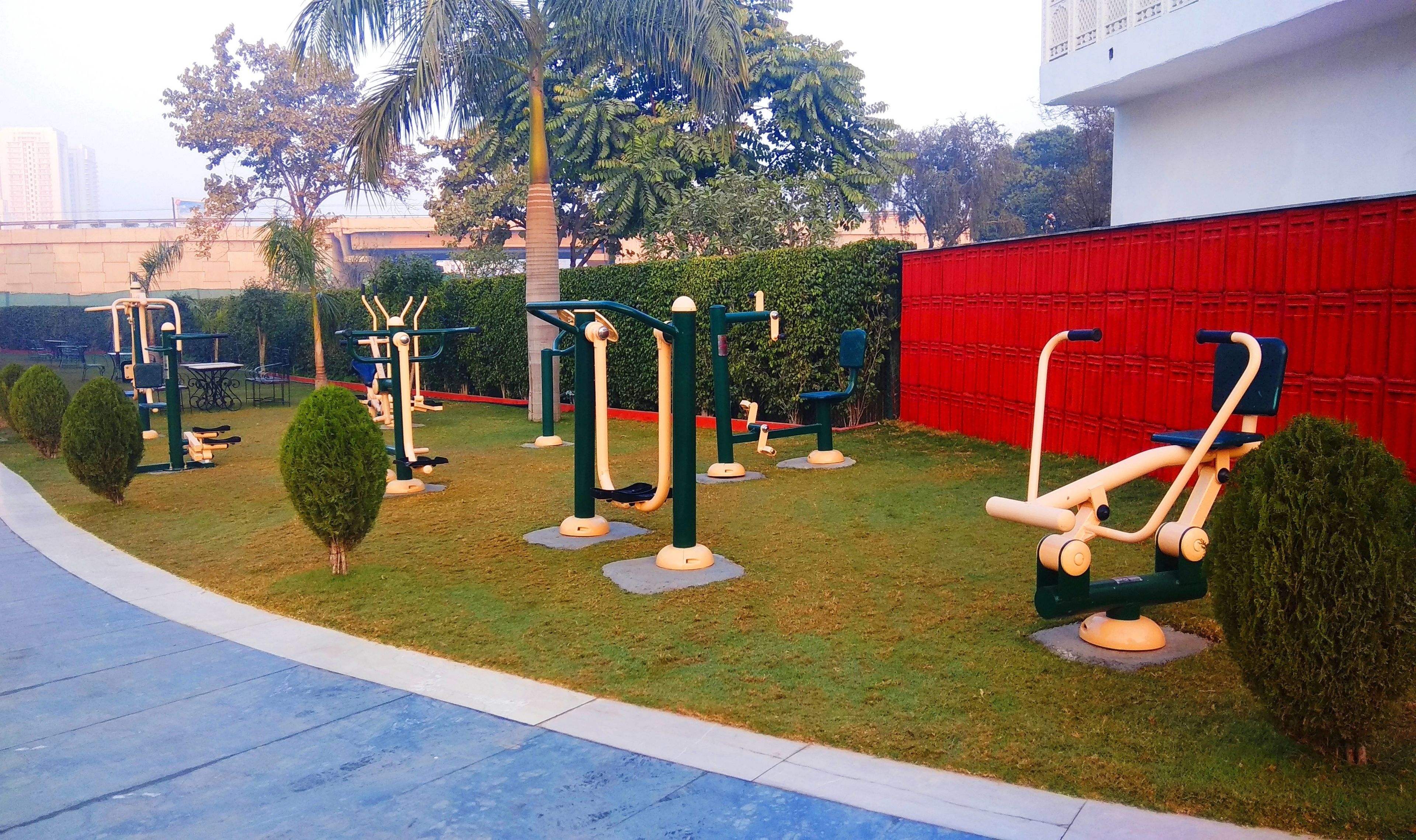 An outdoor gym area with exercise equipment, a red wall, and a blue pathway.