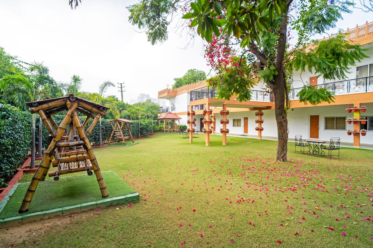 Un patio con un columpio, un edificio con balcones y un árbol de flores rosadas.
