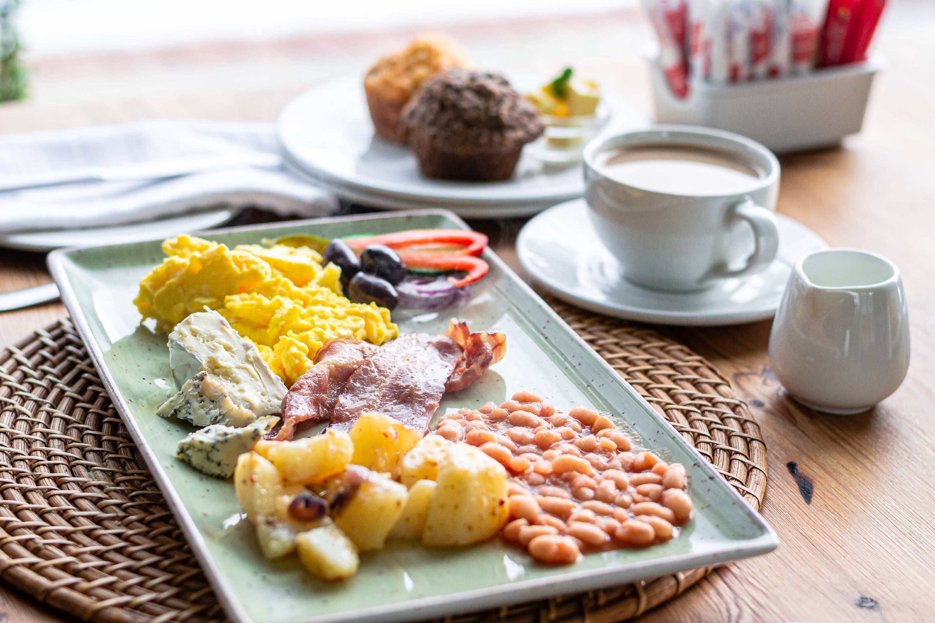 A breakfast plate with eggs, bacon, beans, and potatoes.