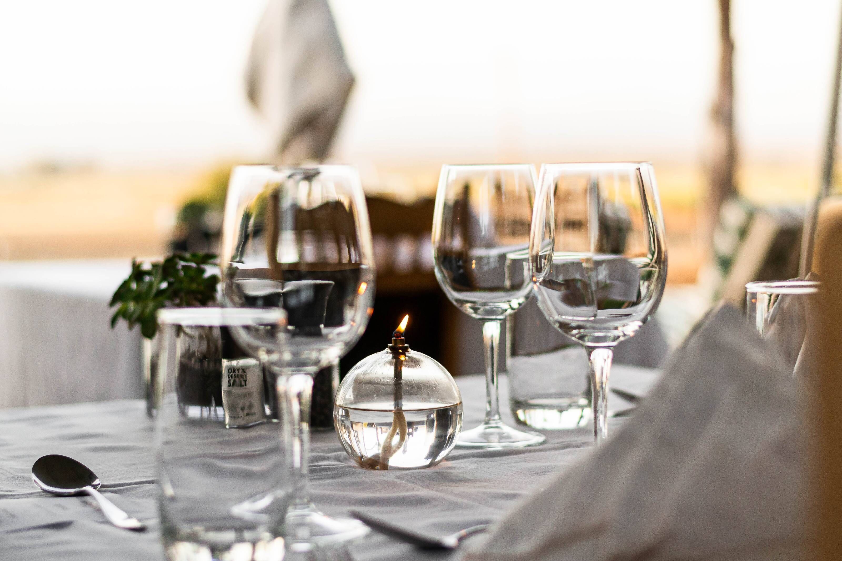 A table set with wine glasses, a salt shaker, and a candle.