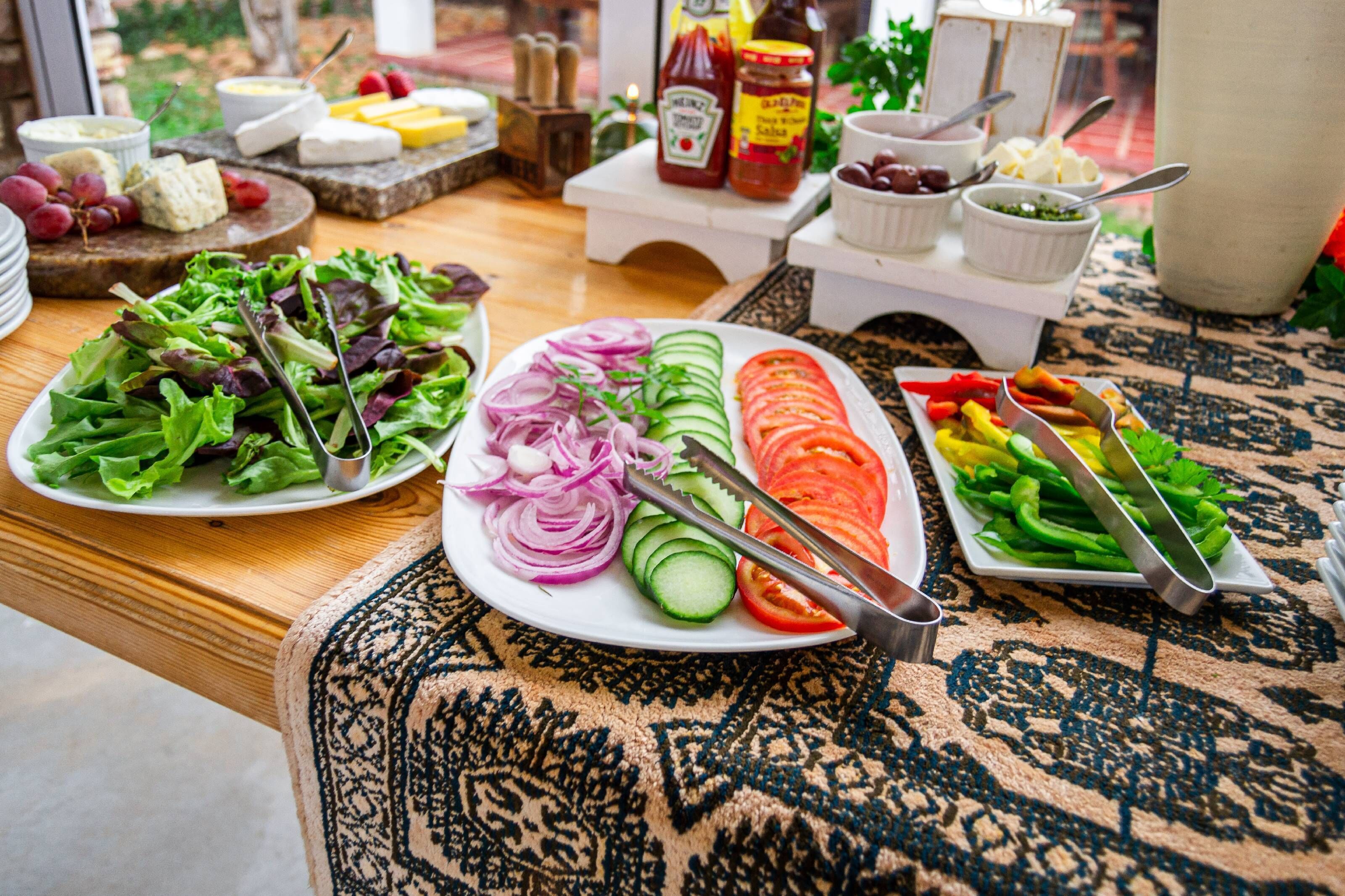 A table with various food items including salads, sliced vegetables, and cheese.