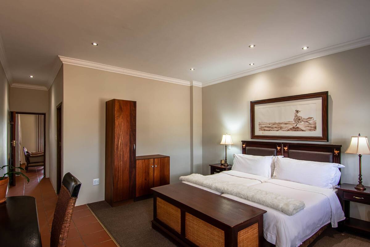 Ein Hotelzimmer mit einem großen Bett, einem Holzschrank, einem Schreibtisch mit Stuhl und einem gerahmten Bild an der Wand.
