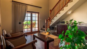 A spacious living area with a wooden staircase, a dining table, and a view of the outdoors. - Mooiplaas Guesthouse (Oudtshoorn)