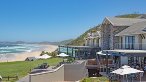 A coastal hotel with a glass conservatory overlooking the beach, outdoor seating, and a view of the ocean. - Brenton Haven Beachfront Resort (Knysna)