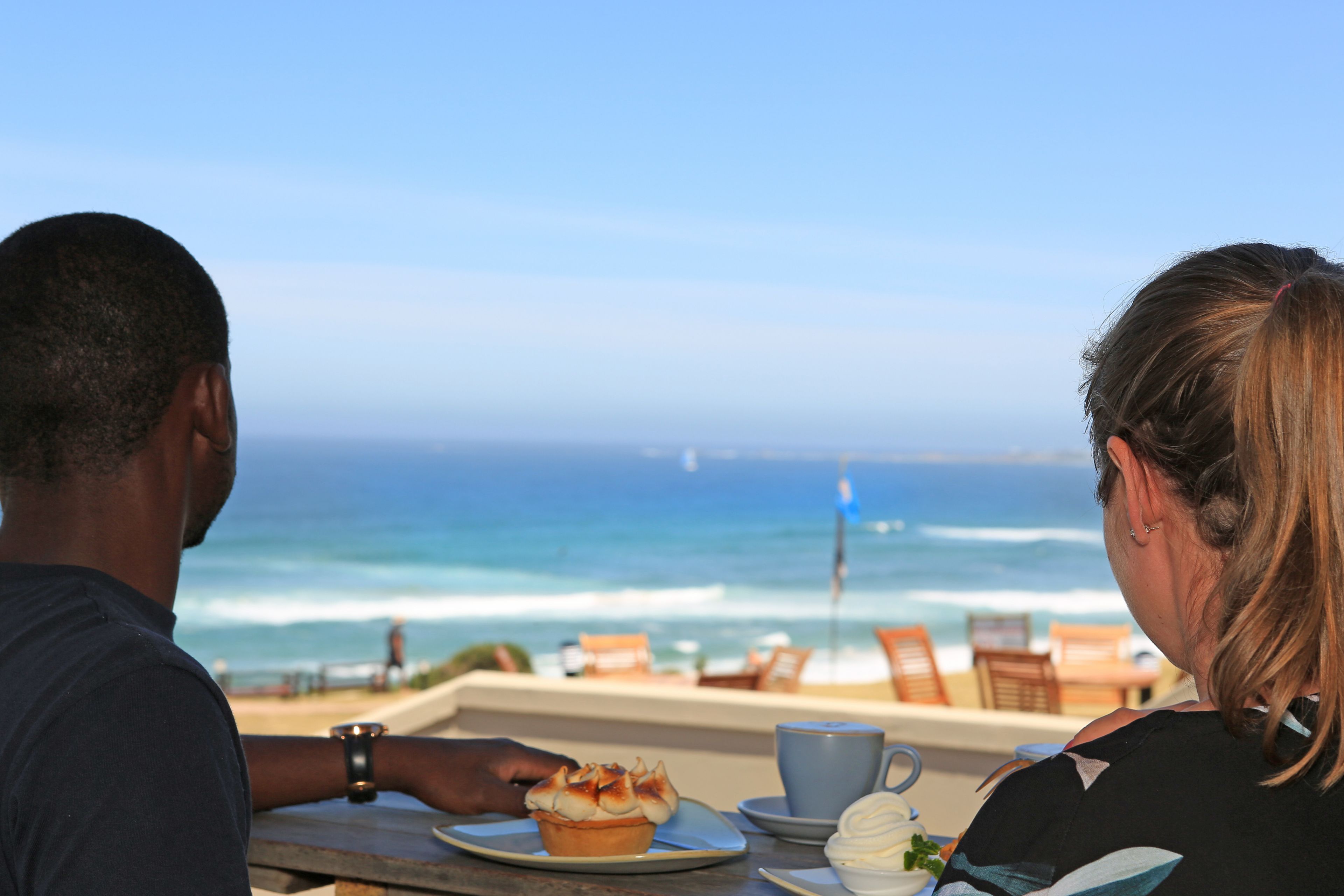 A couple dining at a table with a view of the ocean.