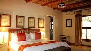 A bedroom with a bed, two bedside tables, a nightstand, a bench, a window with curtains, and framed botanical prints on the wall. - Diemersfontein Wine and Country Estate (Wellington)