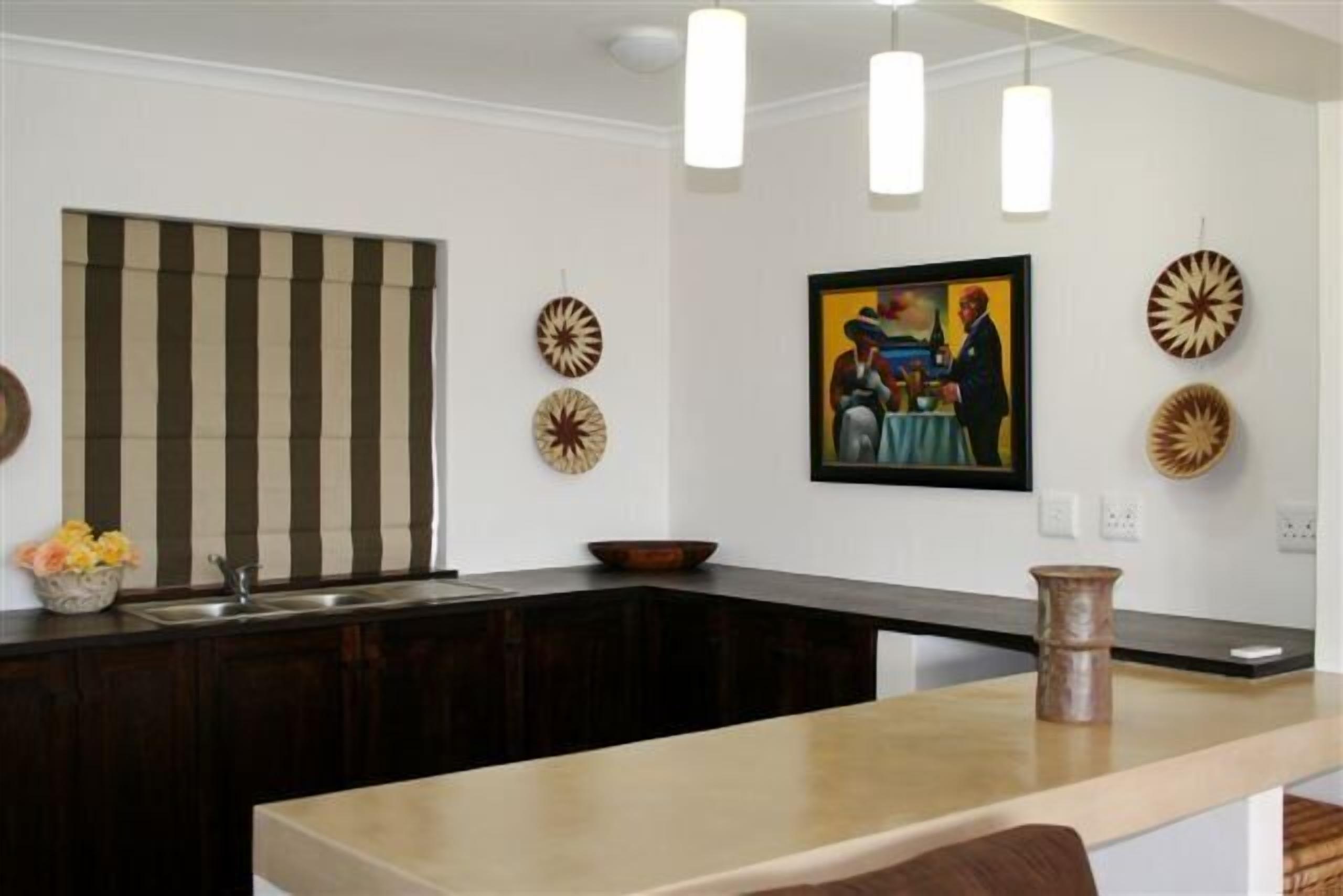 A modern kitchen with a dark countertop, a striped window blind, and decorative plates on the wall.