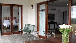A hotel room with a bed, a green bench, a dining table with chairs, and a vase of flowers. - Diemersfontein Wine and Country Estate (Wellington)
