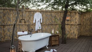 A rustic outdoor bathroom with a freestanding bathtub, a wooden bench, and a lantern. - Mount Camdeboo Private Game Reserve by NEWMARK (Blue Crane Route)