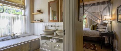 A bathroom with a large bathtub, a double sink, and a mirror above the sink.
