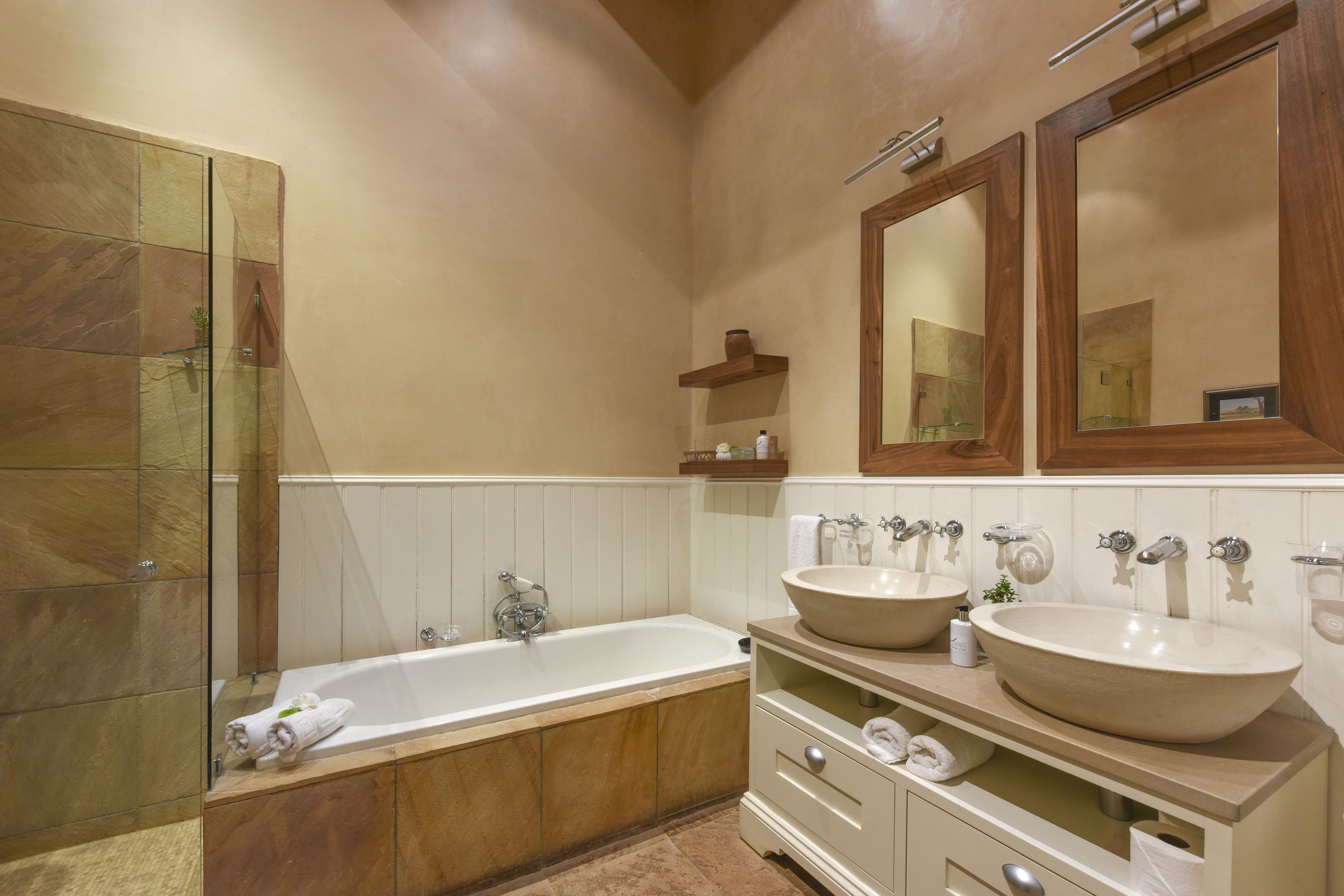 A modern bathroom with a large bathtub, two sinks, and a glass shower enclosure.