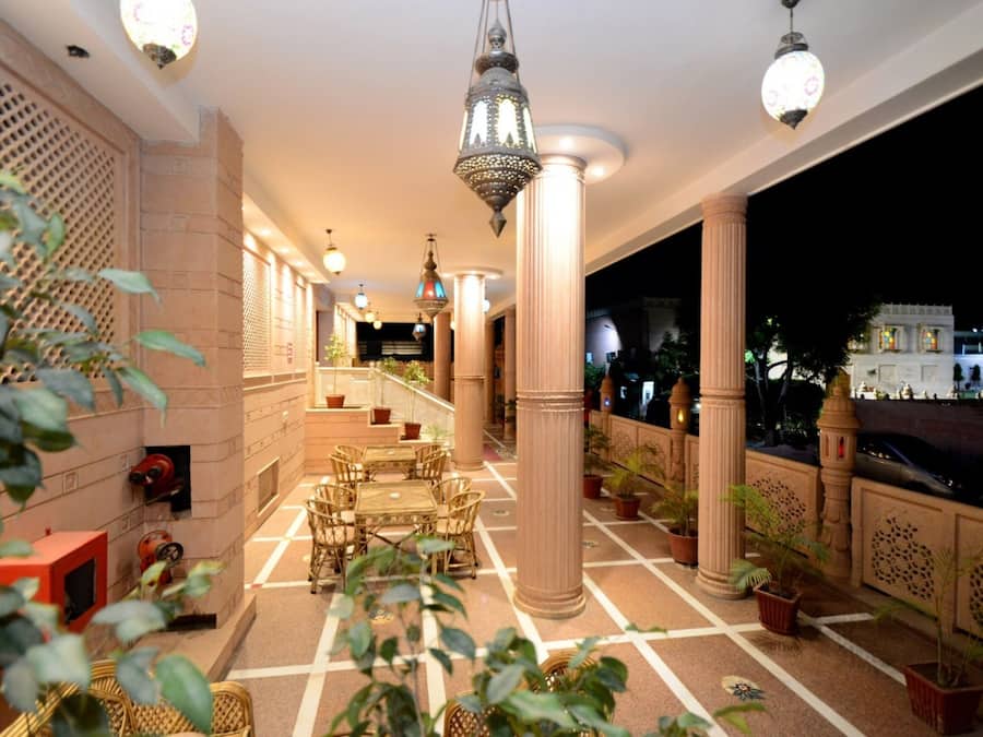 A well-lit indoor area with columns, a seating area, and potted plants.