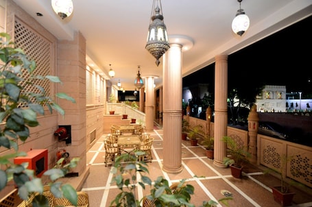 A well-lit indoor area with columns, a seating area, and potted plants.