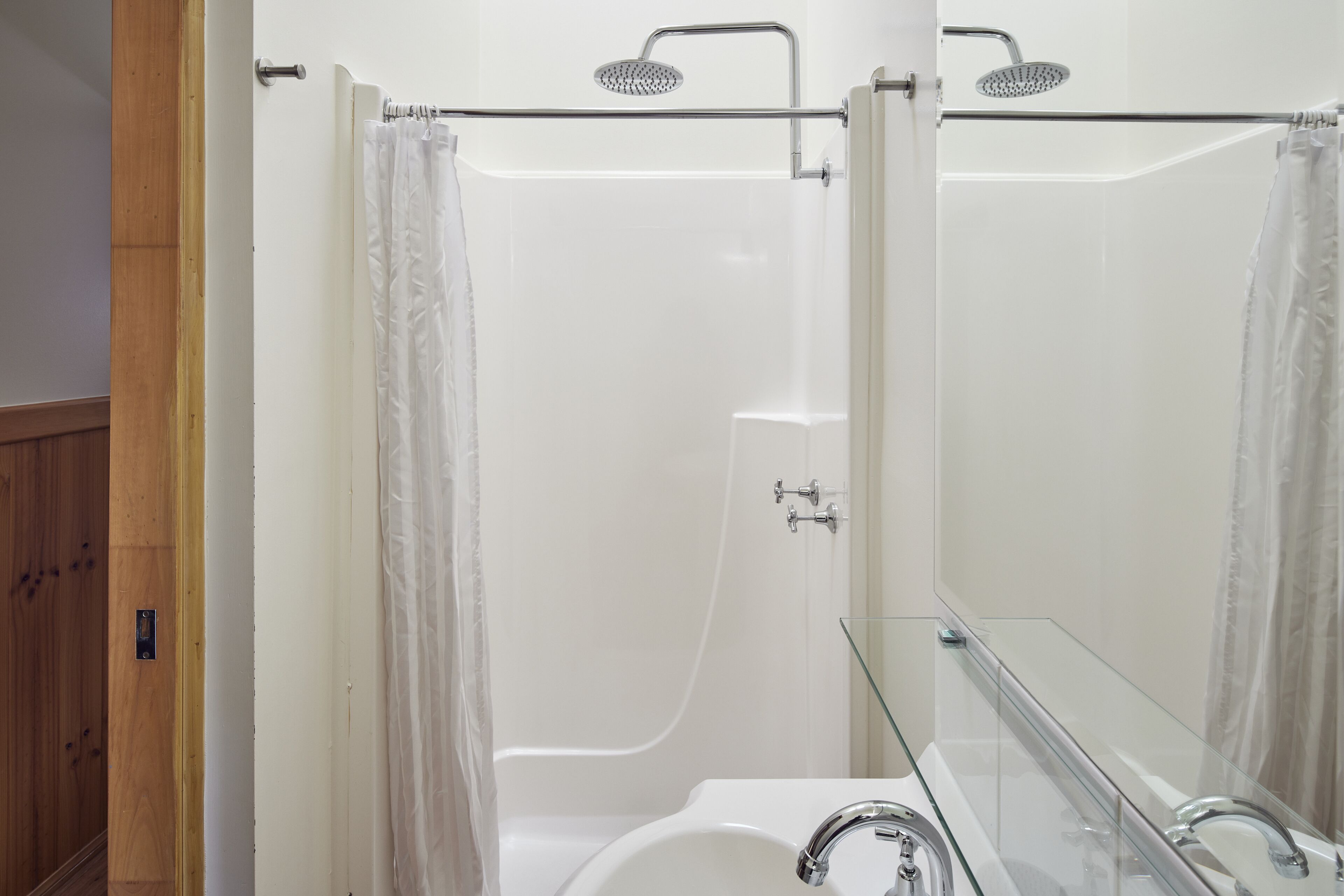 A modern bathroom with a glass shower enclosure, a white bathtub, and a glass-enclosed vanity.
