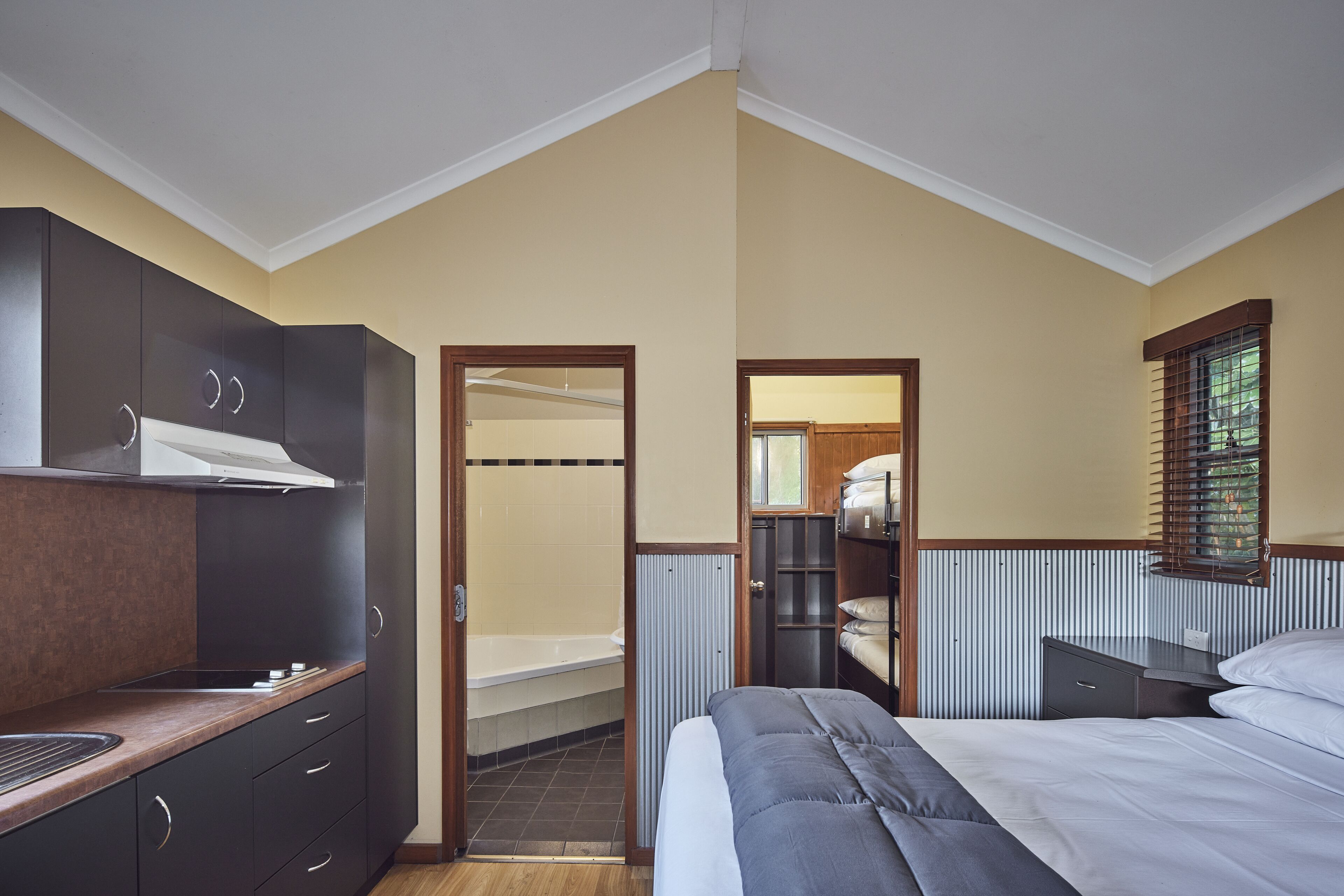 Une chambre de taille modeste comprenant un lit, un petit bureau, un coin cuisine et une salle de bain.