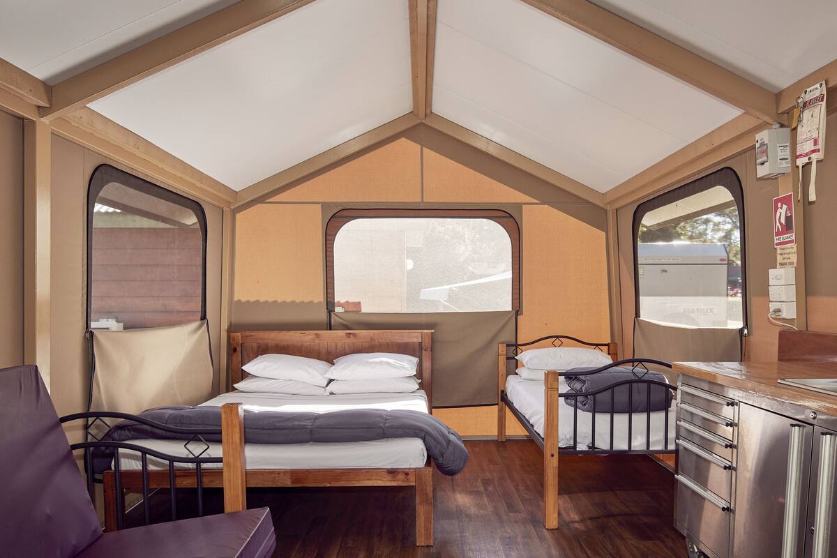A compact, well-lit room with a bed, a small desk, and a chair.