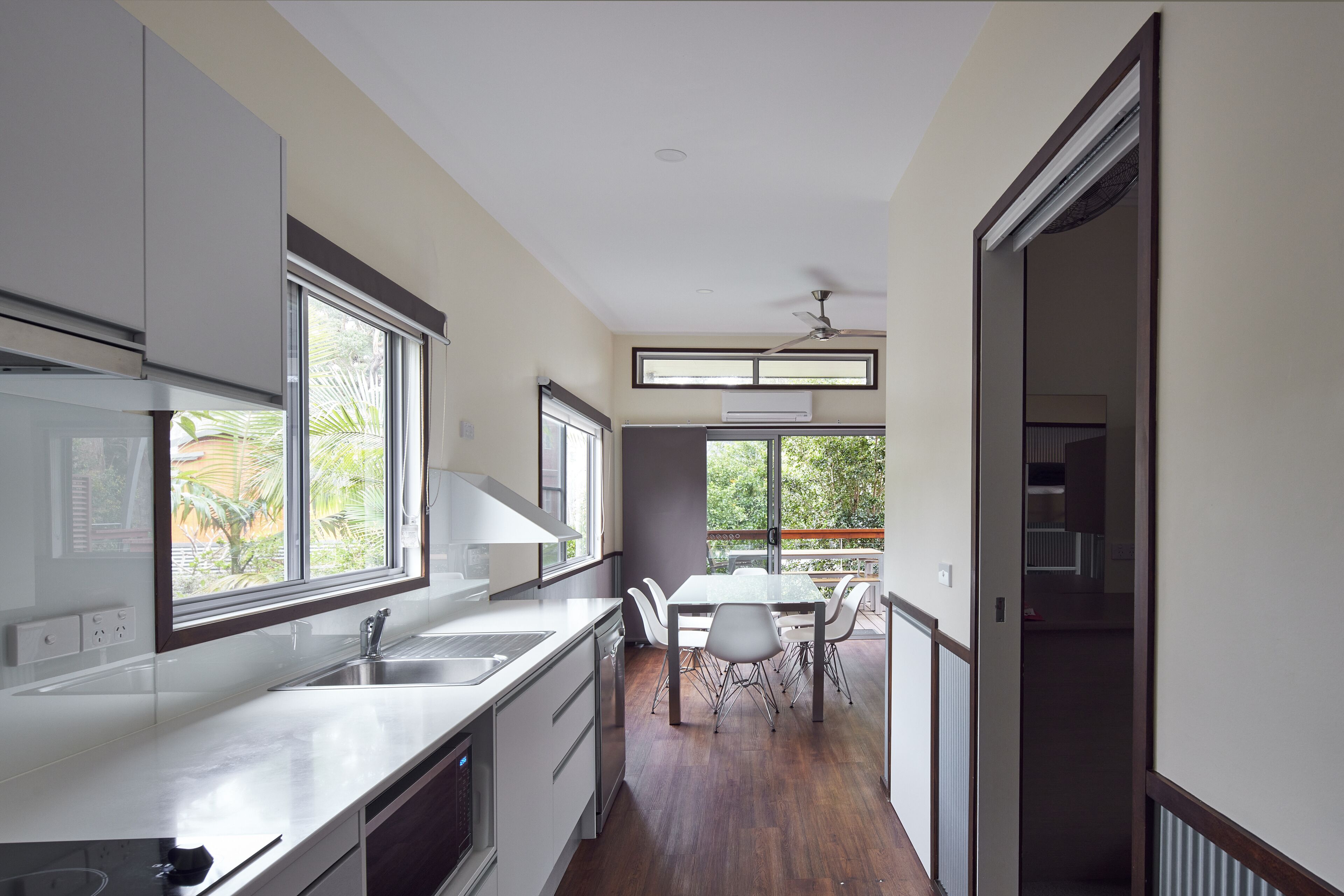 Une cuisine moderne dotée d’une grande fenêtre, un coin repas avec une table et des chaises, et une vue sur l’extérieur.