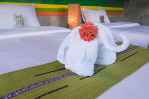 A bed with a white blanket and a decorative towel shaped like an elephant with a red flower on its back. - Baan Chokdee Pai Resort (Pai)