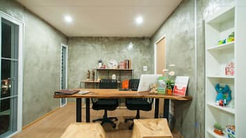 Una sala de conferencias con una mesa de madera, dos sillas de oficina negras, una computadora portátil y un cartel que anuncia un hotel.