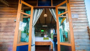 A wooden cabin with a bed, curtains, and a sign with the number 123. - Baan Chokdee Pai Resort (Pai)