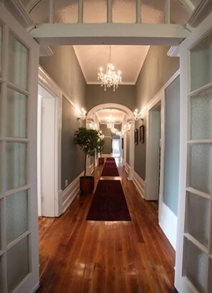 A hallway with wooden flooring, white doors, and a red carpet leading to a room. - Park Place Boutique Guesthouse (East London)