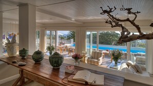 A spacious room with a wooden table, a large window overlooking a pool, and a view of the outdoors. - Sea Five Boutique Hotel (Cape Town)