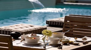 A poolside dining setup with a table, chairs, and a view of the pool. - Sea Five Boutique Hotel (Cape Town)