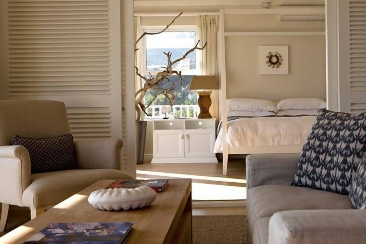 Ein Zimmer mit einem Bett, einem Schlafsofa, einem Sessel und einem Tisch. Ein Fenster bietet Blick auf das Meer.