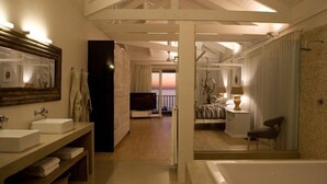 A modern bathroom with a bathtub, a large mirror, and a vanity with two sinks. - Sea Five Boutique Hotel (Cape Town)