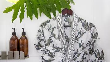 A room with a white wall, a hanging plant, and two brown bottles on a shelf.