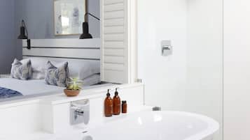 Une salle de bain moderne avec une baignoire sur pieds, une douche à parois de verre et un meuble-lavabo blanc avec un miroir.