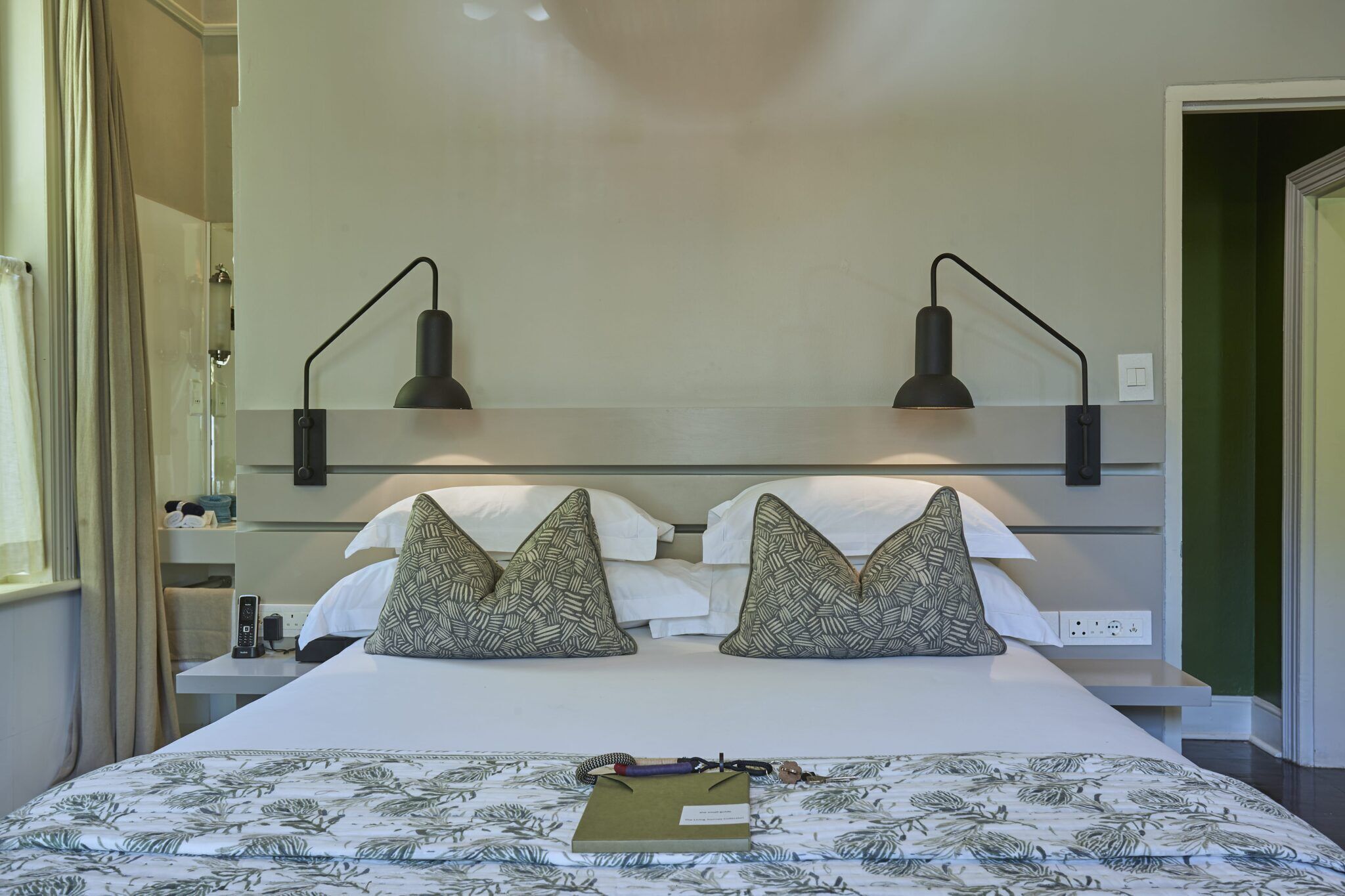 A hotel room with a bed, two bedside lamps, a telephone, and a nightstand.