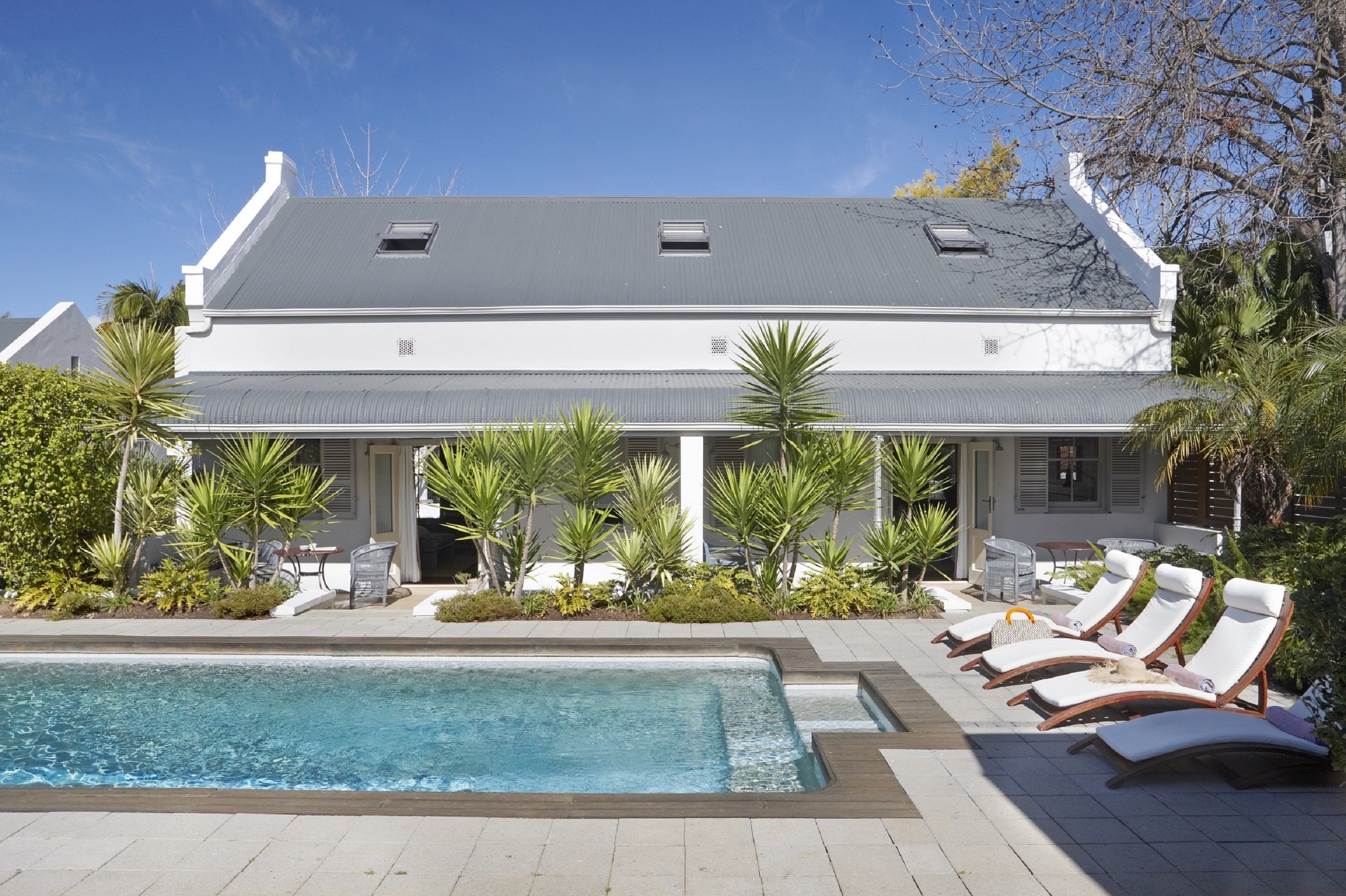 A two-story house with a swimming pool and sun loungers.