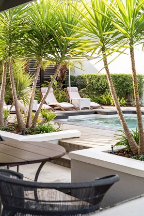 A poolside area with lounge chairs, a small table, and palm trees. - The Robertson Small Hotel (Robertson)