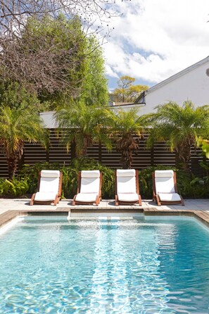 A swimming pool with four lounge chairs and a wooden deck. - The Robertson Small Hotel (Robertson)