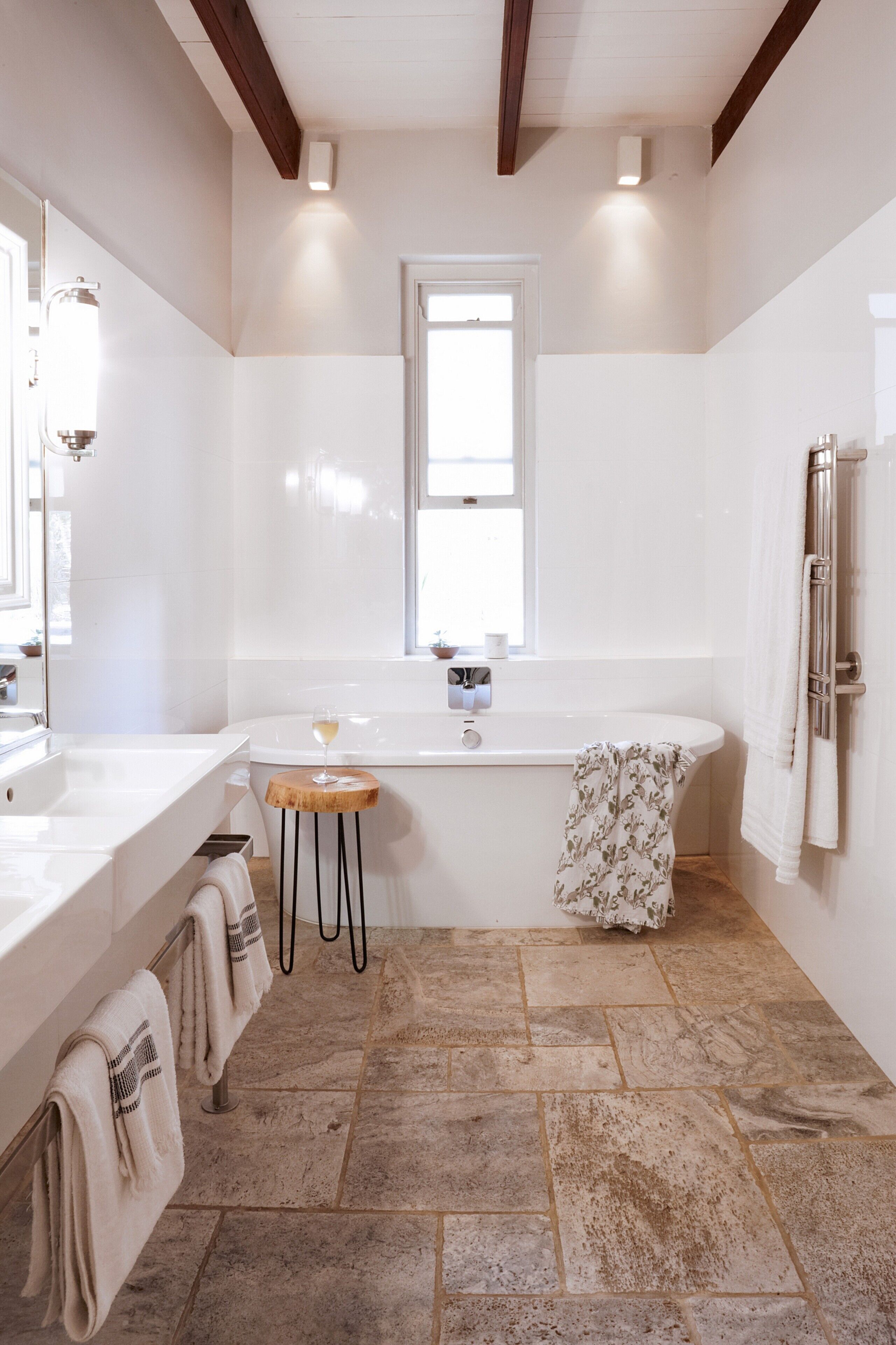 A modern bathroom with a large bathtub, a vanity with a mirror, and a window providing natural light.