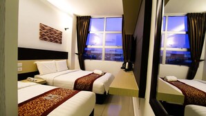 Ein Hotelzimmer mit zwei Betten, einem Fernseher, einem Fenster mit Vorhängen und einem Wandbild.