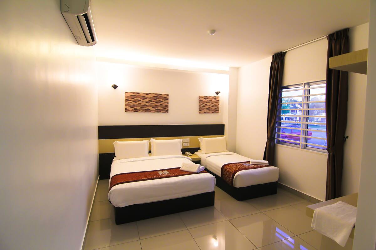 A hotel room with two beds, a bathroom, and a window with curtains.