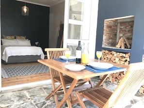 Ein Zimmer mit einem Bett, einem Esstisch mit Stühlen, einer Weinflasche und Gläsern Orangensaft.