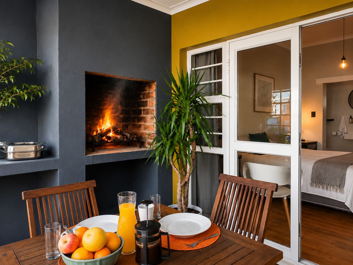 Un comedor con chimenea, una mesa dispuesta para el desayuno y vista al dormitorio.