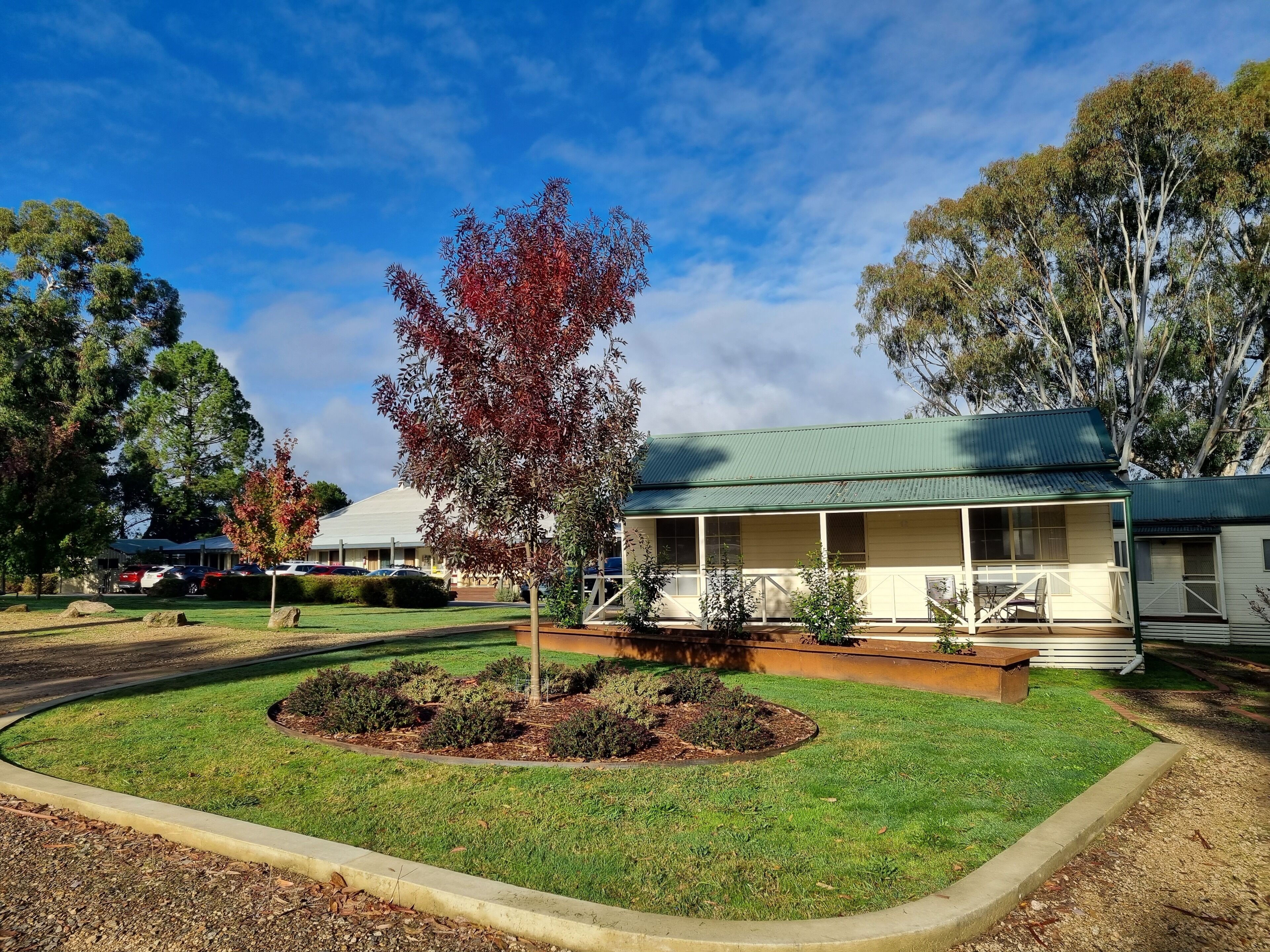 A two-story building with a green roof, surrounded by a well-maintained lawn and a small garden area.