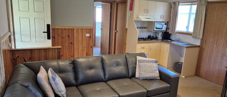A compact living space with a sofa, a coffee table, and a kitchenette area.