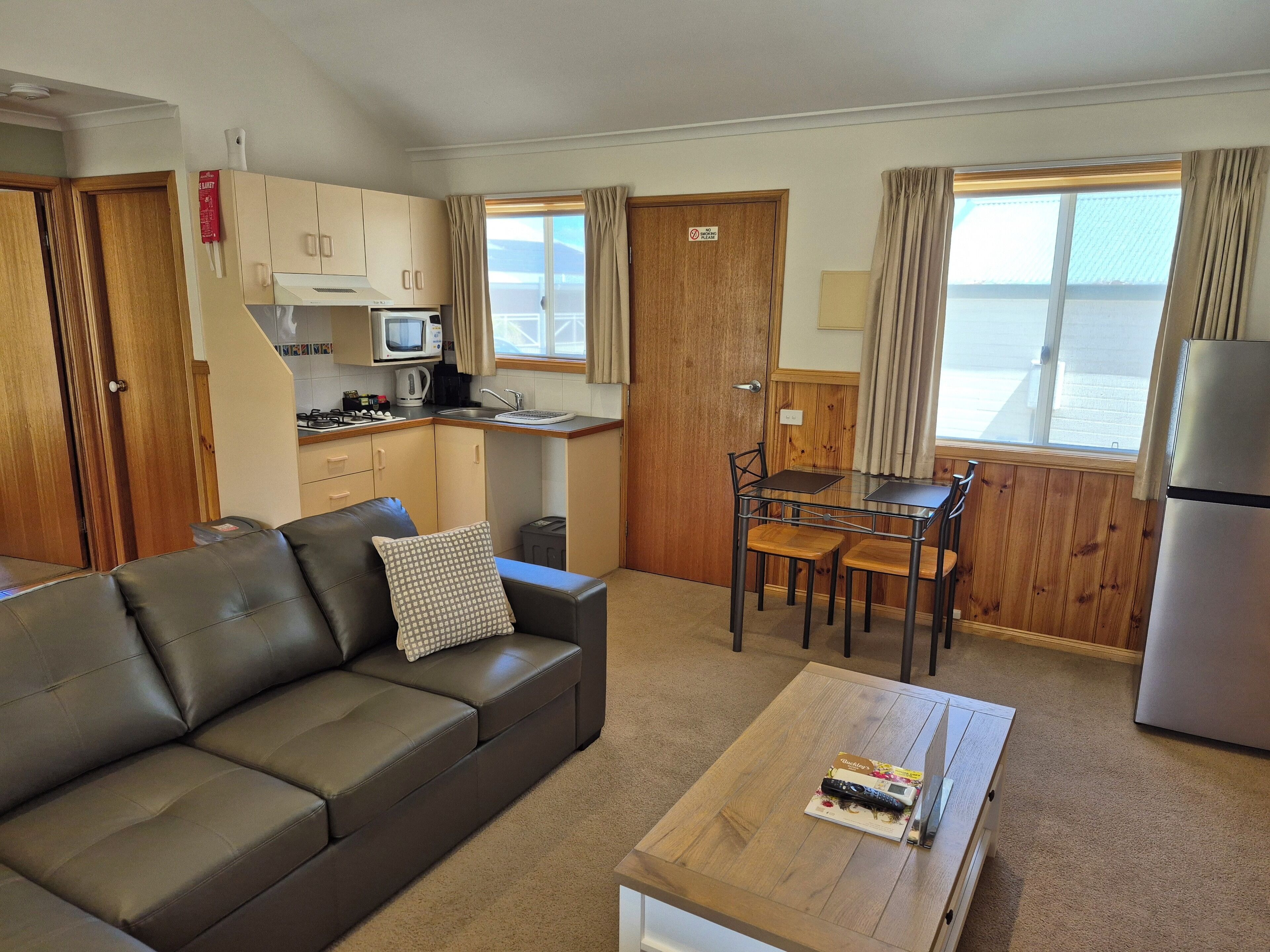 Un espacio habitable compacto con kitchenette, comedor, sofá y vista al mar.