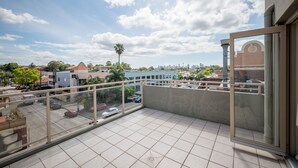 A balcony with a view of a cityscape, including buildings and a palm tree. - Cityview Studio Accommodation (Leichhardt)
