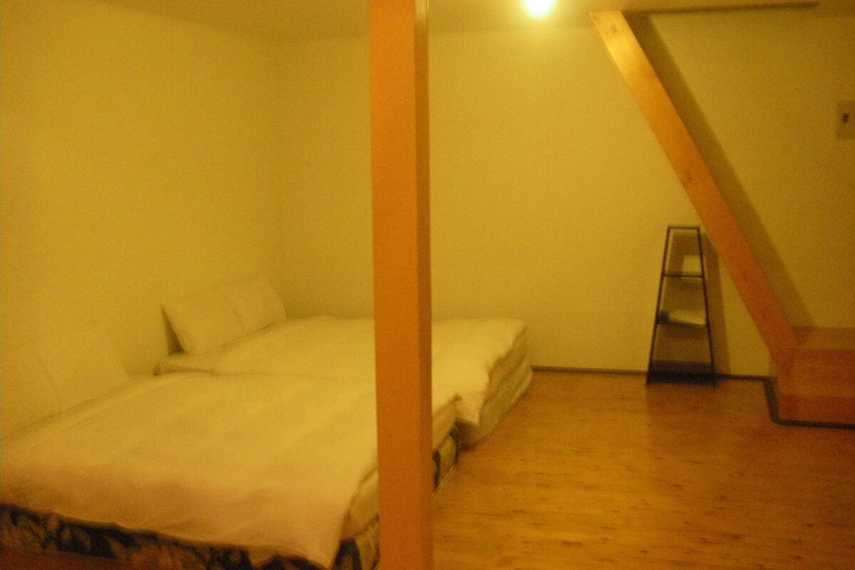 Un dormitorio con cama, una mesita y una escalera de madera.