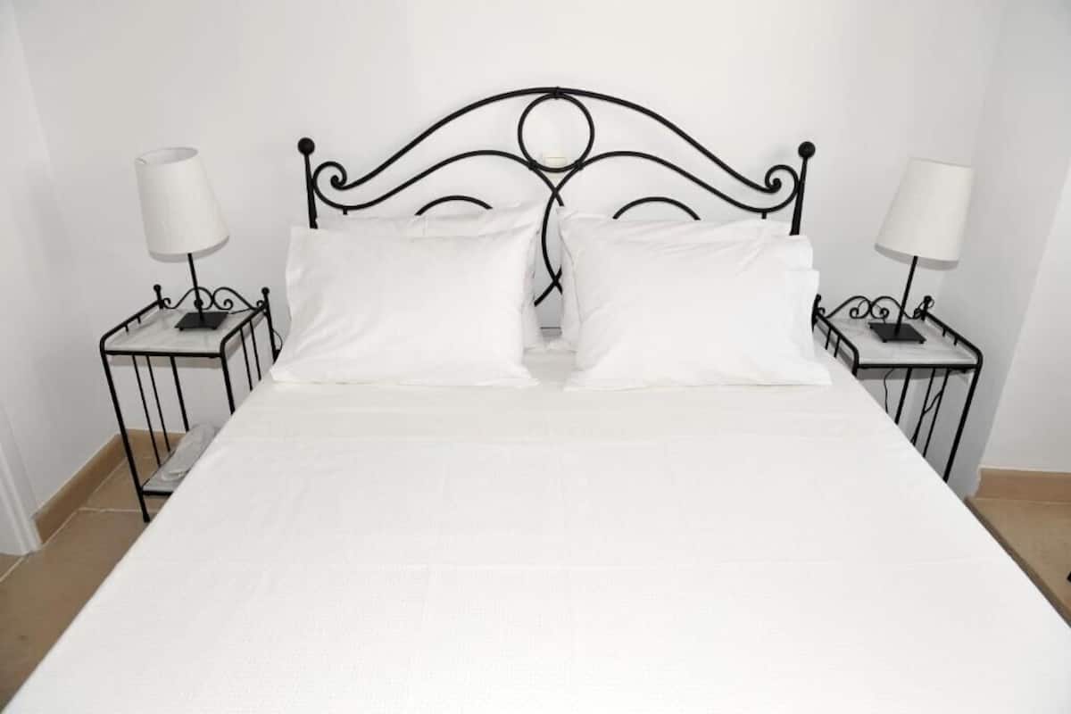 A bed with a metal headboard, two bedside tables with lamps, and white bedding.