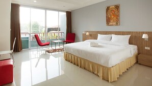 A hotel room with a large bed, a desk, a chair, and a balcony with a view. - Soontree House (Udon Thani)