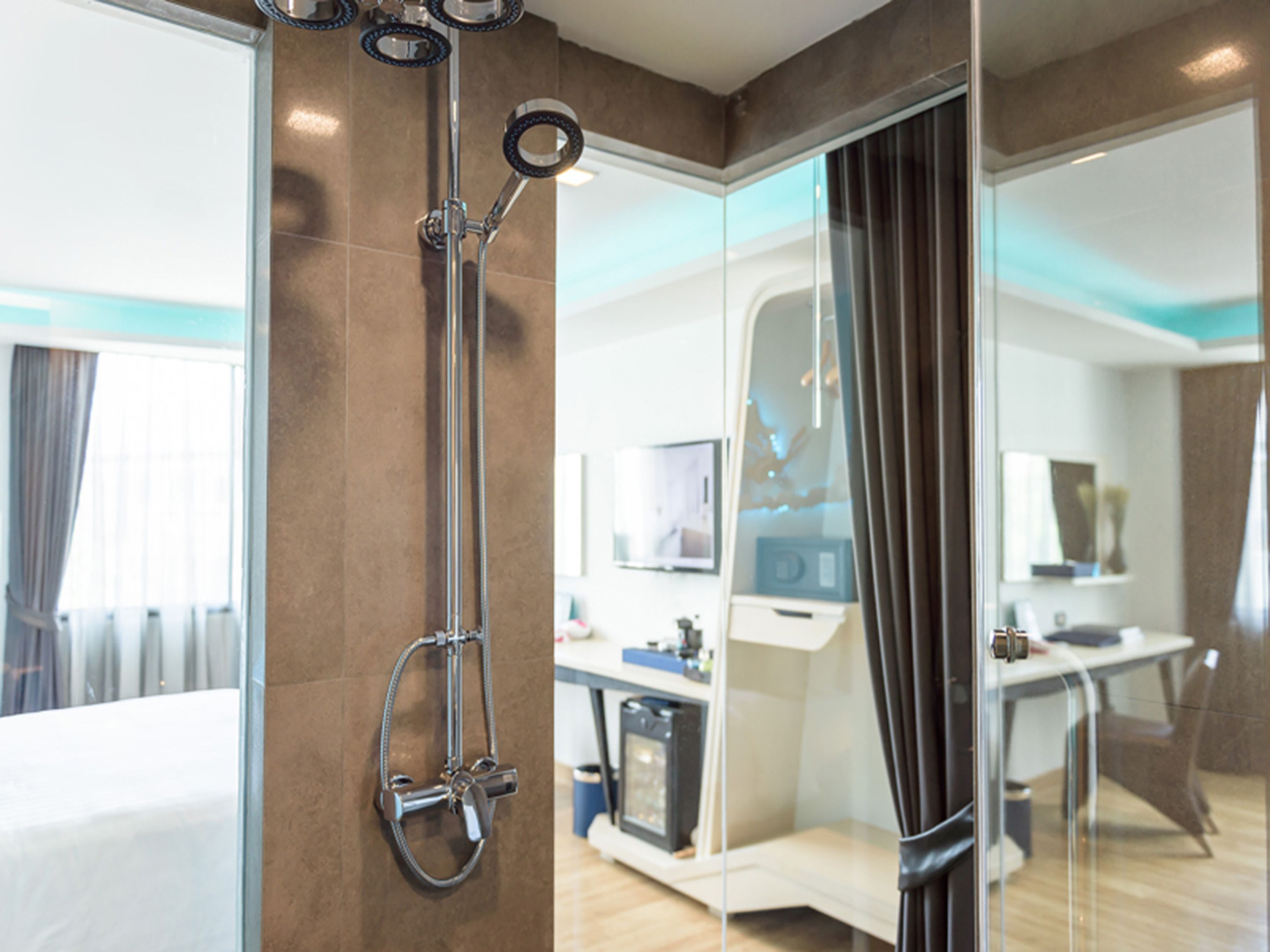 A modern bathroom with a glass shower enclosure, a visible control panel, and a seating area with a table and chairs.