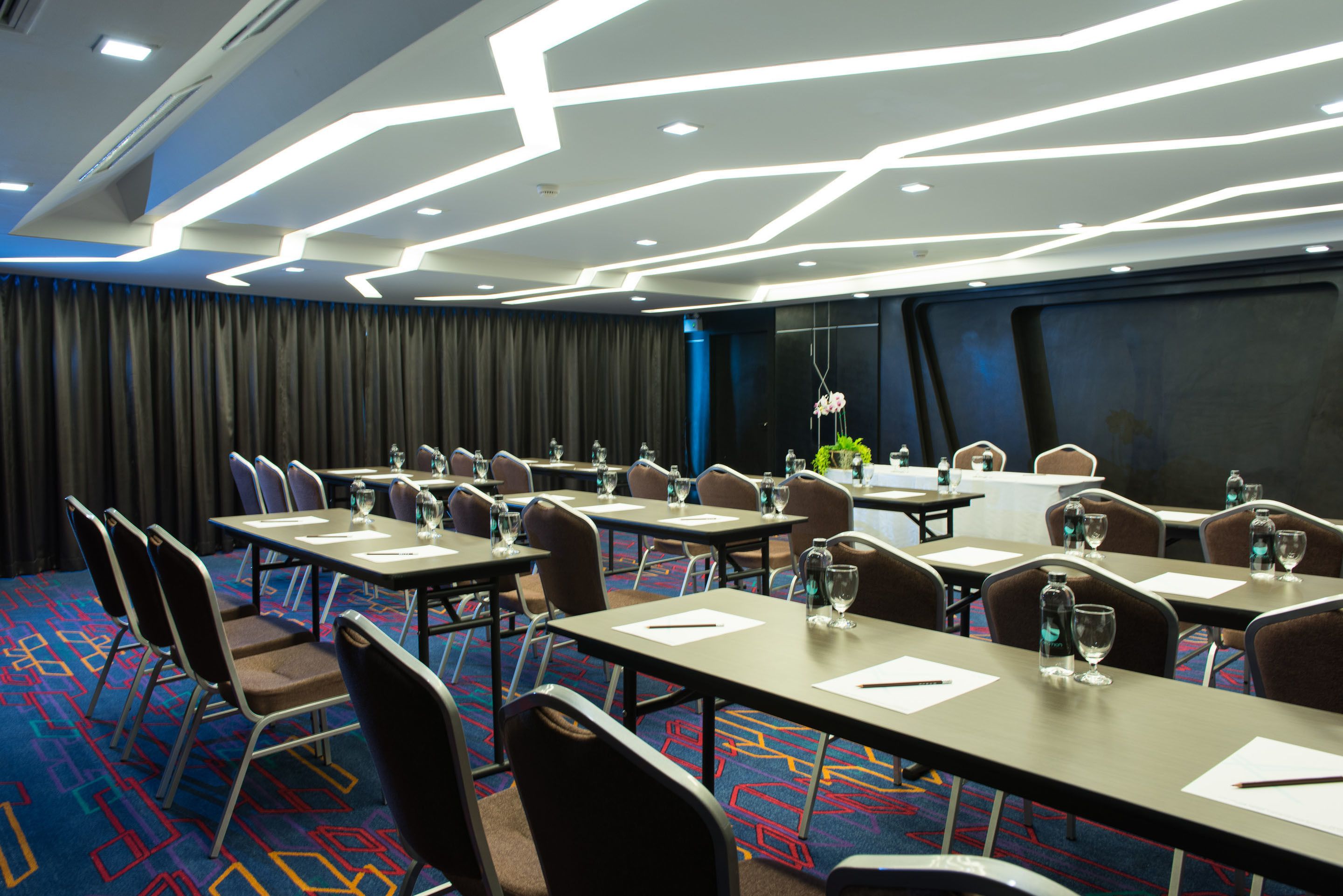 A conference room with tables, chairs, and a patterned carpet.