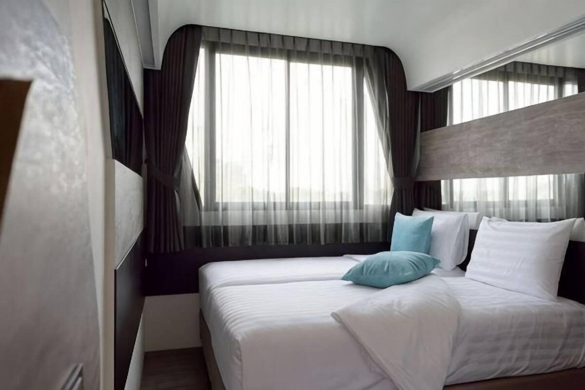A hotel room with a bed, curtains, and a window.
